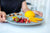 Colorful dessert plate with strawberries, oranges, and a yellow mousse served on a blue plate.